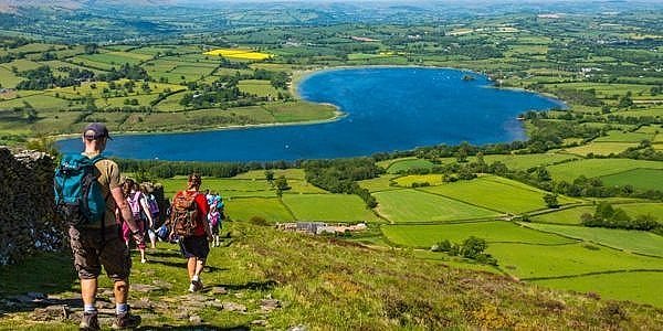 A group of people hiking in the mountain going down towards the lake